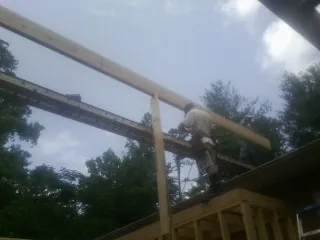 Carpenter setting a ridge beam over a new addition frame — Ice Dam Removal by Roofing Brothers in Honeoye