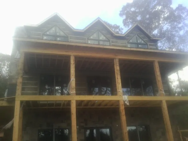 Dormers and porch framing on a large log home under construction — Roof Coating work by our crew in Honeoye
