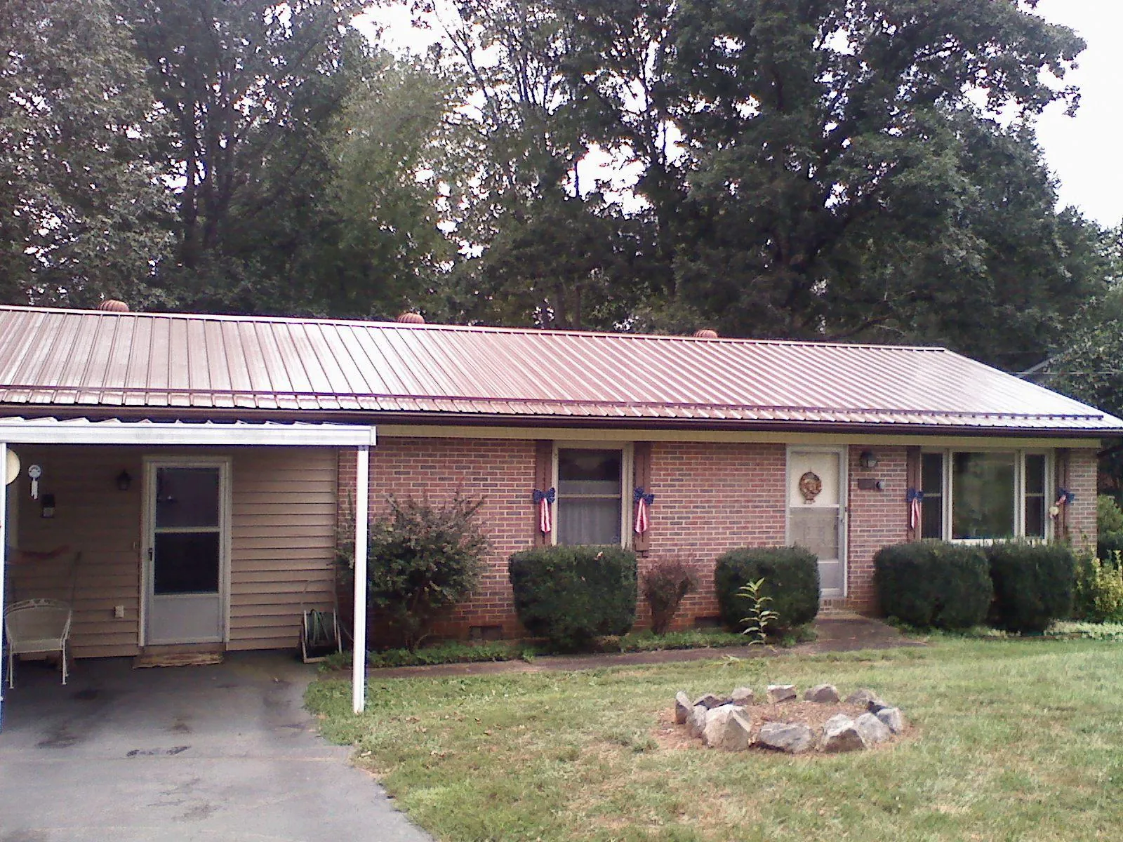 Bronze metal roof and carport on a brick ranch home — Roof Repair work by our crew in Honeoye