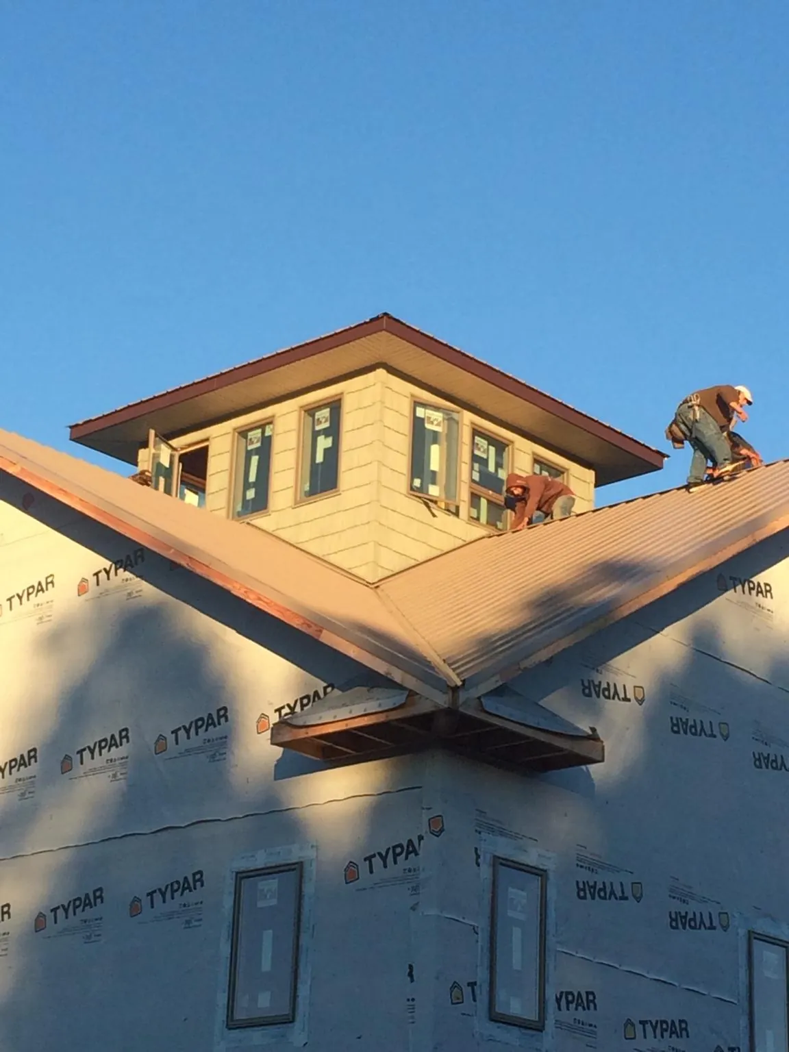 Roofers working around a rooftop cupola on a new metal roof at sunset — Roof Waterproofing in Honeoye by Roofing Brothers